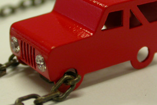 Suzi Zutic: Sterling silver jeep necklace in car enamel, white sapphires (set as headlights), garnets (set as tail lights). POA.